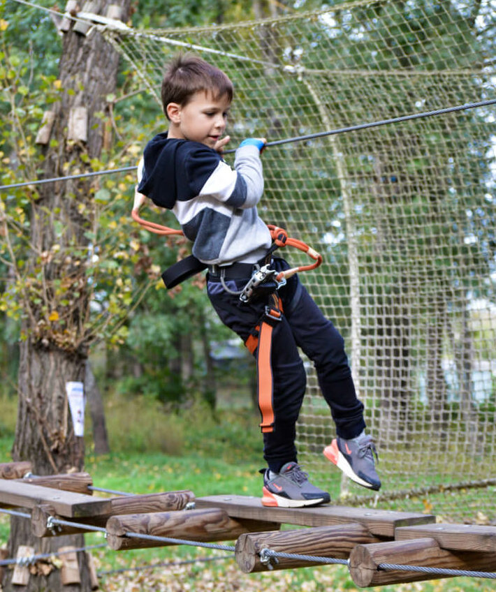 enfant dans un accrobranche sur un jeu d'équilibre